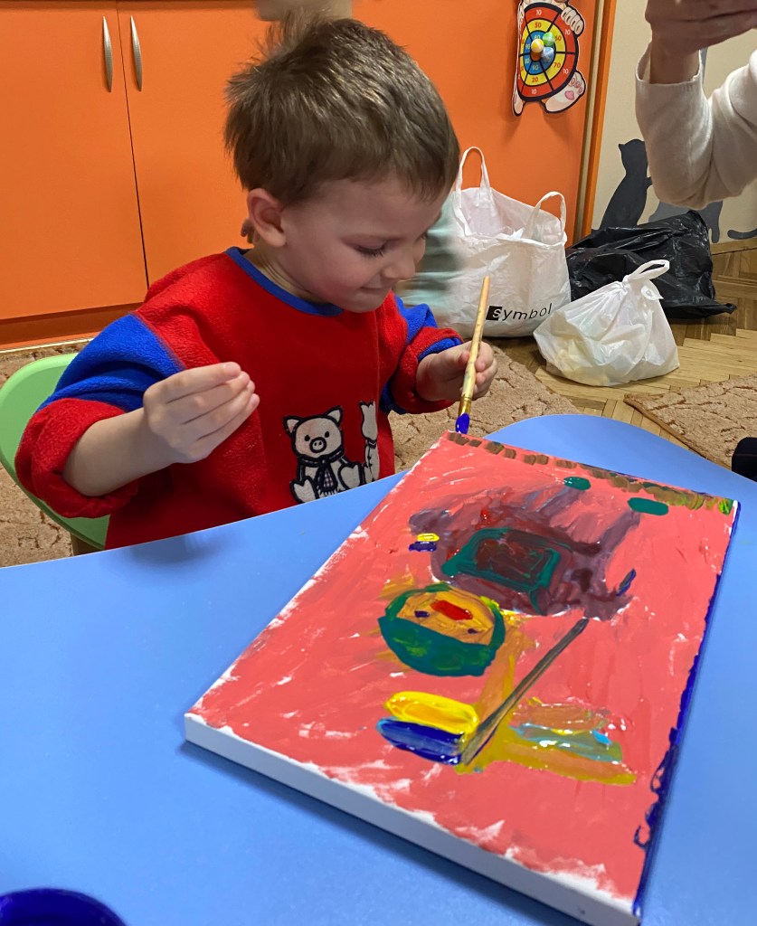 A displaced child painting a Ukrainian solider at a Painting the Future art workshop in an orphanage in Ukraine.