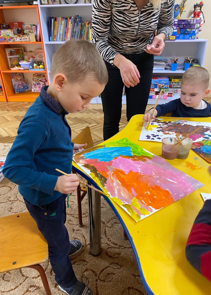 Two displaced children painting at a Painting the Future art workshop in an orphanage in Ukraine.
